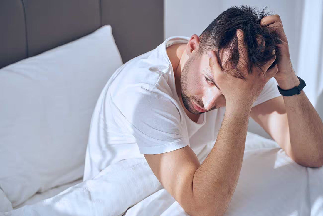 Person sitting on bed in the morning appearing exhausted, illustrating chronic fatigue and low energy despite sleep