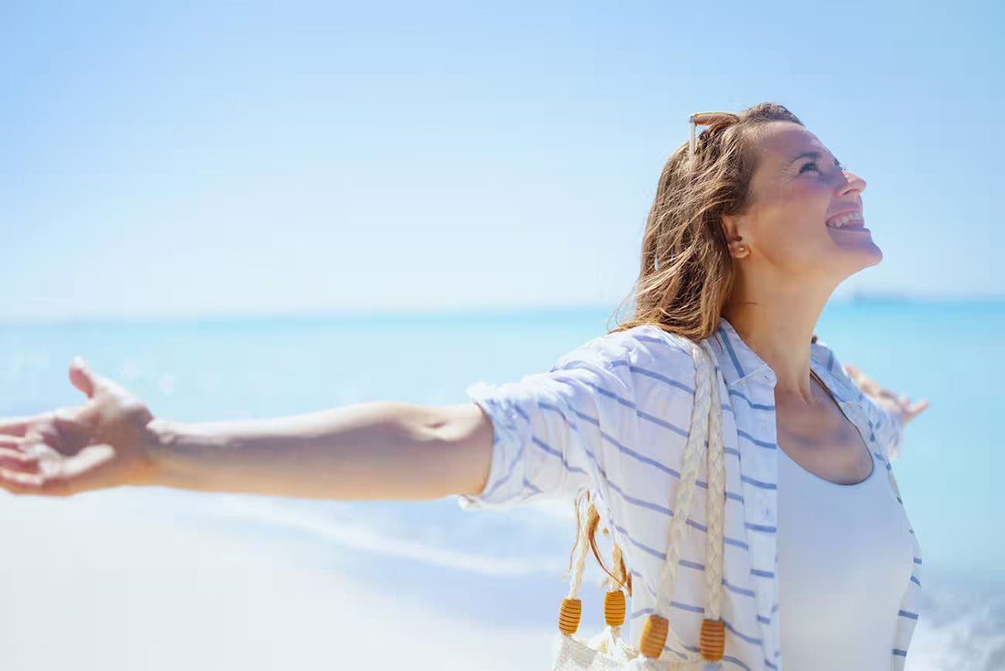 Person standing on a sandy beach with arms outstretched