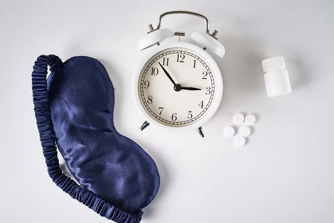  sleep mask, alarm clock, and pills on white background