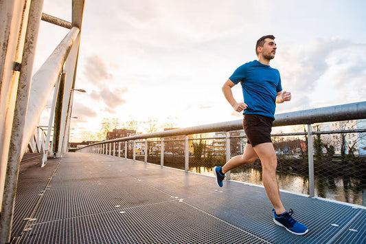 Person jogging outdoors on an urban bridge, illustrating exercise and lifestyle habits that support cellular health and NAD+ production.